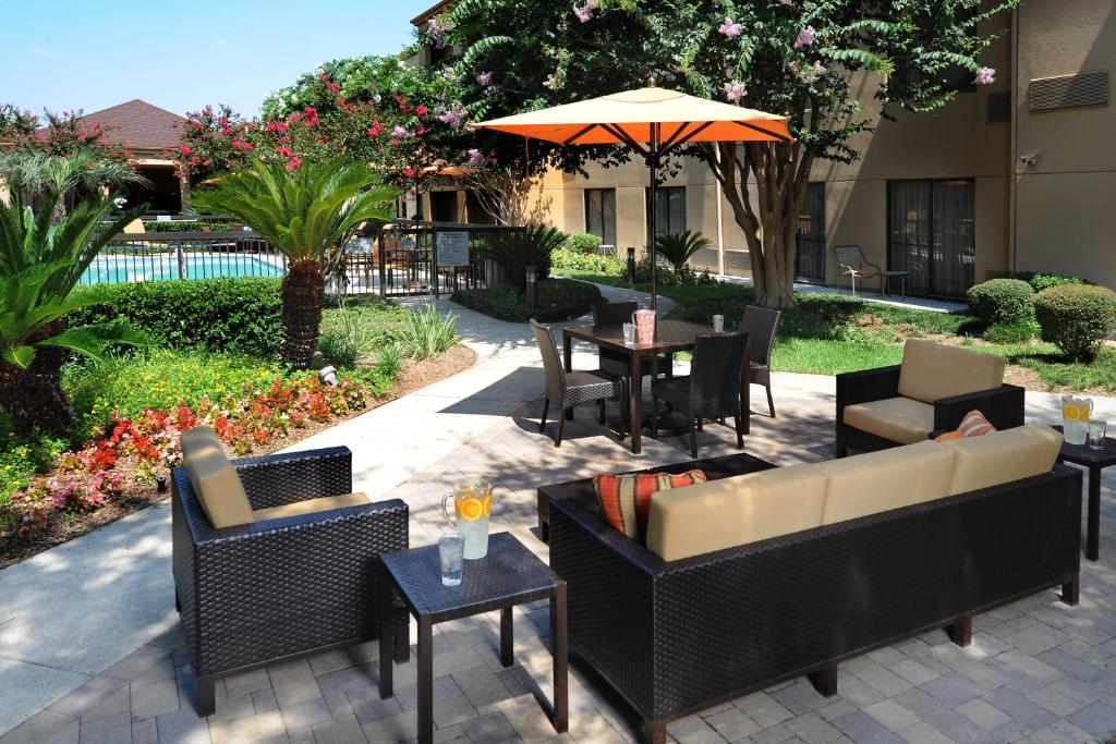 a patio with couches and tables and an umbrella at Courtyard by Marriott Houston Hobby Airport in Houston