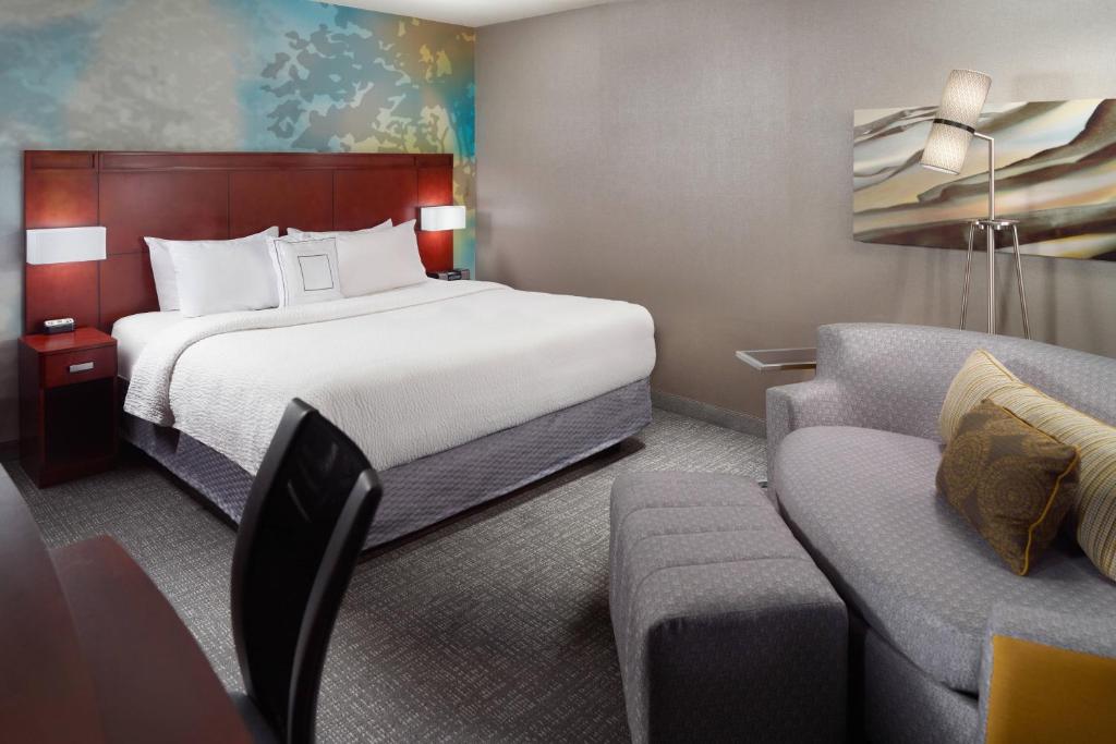 a hotel room with a bed and a couch at Courtyard by Marriott Atlanta Buckhead in Atlanta