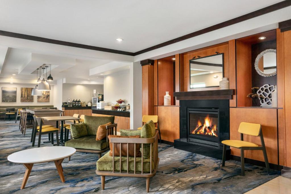 a living room with a fireplace and tables and chairs at Fairfield Inn & Suites Stillwater in Stillwater