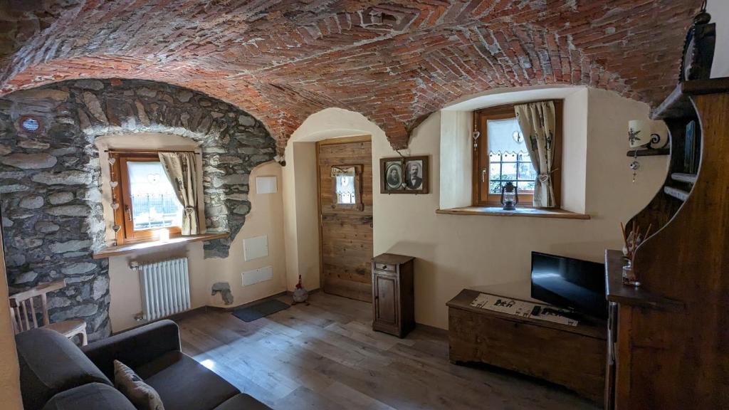 een woonkamer met een bank en een stenen muur bij Maison du Pont Romain in Aosta