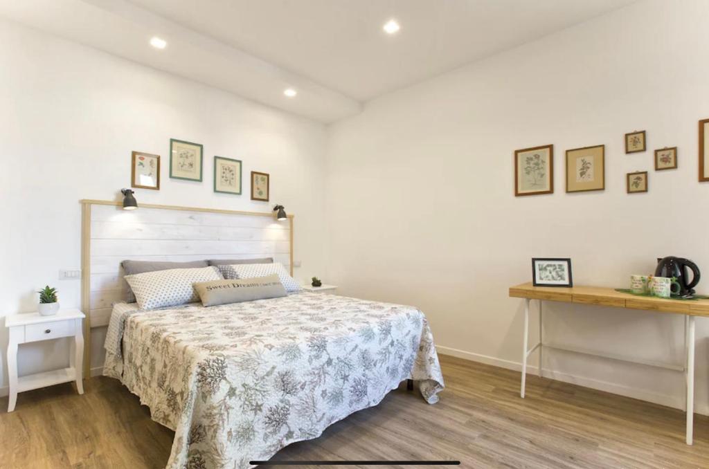 a white bedroom with a bed and a table at Catalogna10 Rooms in Alghero