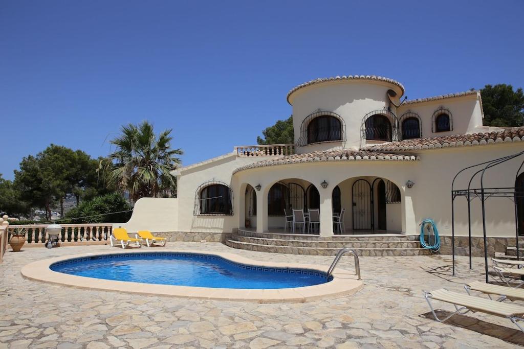 una casa con piscina frente a ella en Superb villa with heated private pool - stunning sea and mountain views- Air con en Teulada