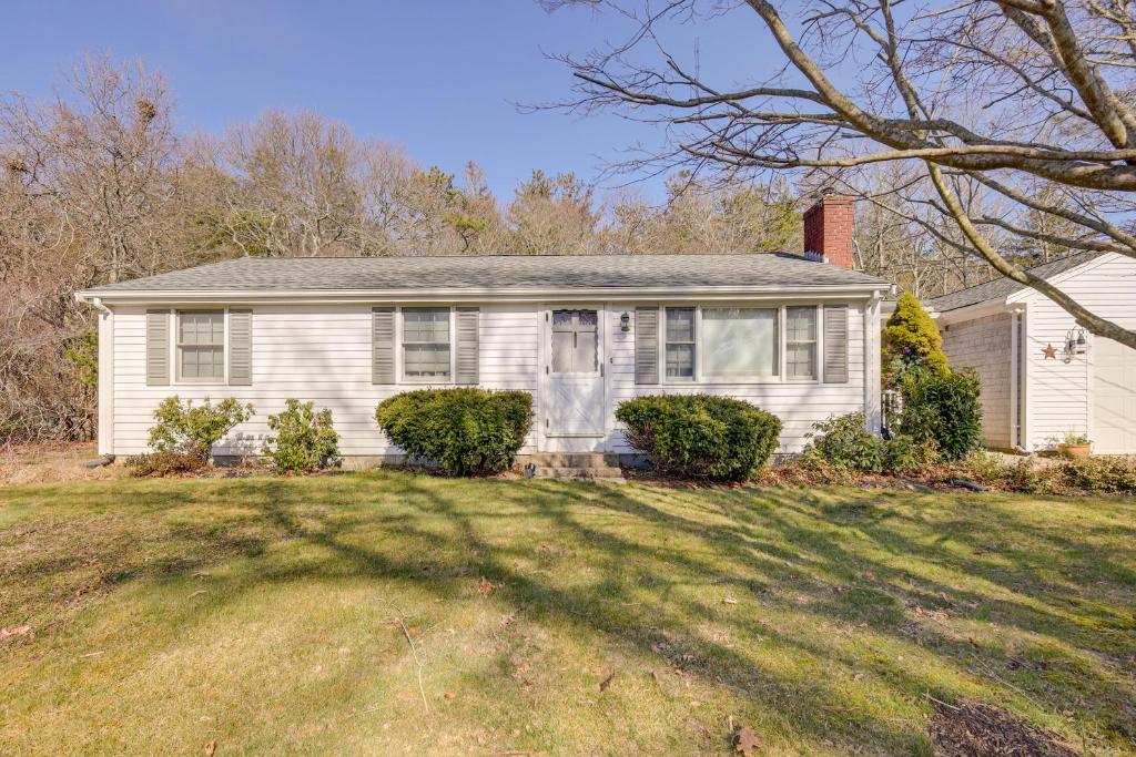 a white house with a tree in a yard at Picturesque Barnstable Rental with Deck and Backyard! in Barnstable