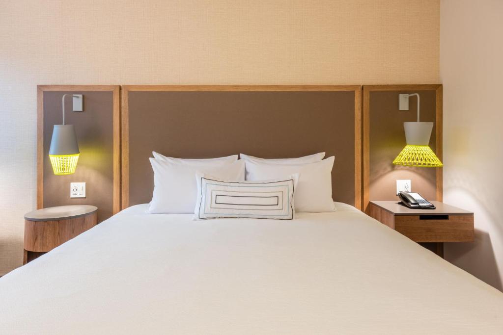 a bedroom with a large white bed with two lamps at Fairfield by Marriott Medellin Sabaneta in Medellín