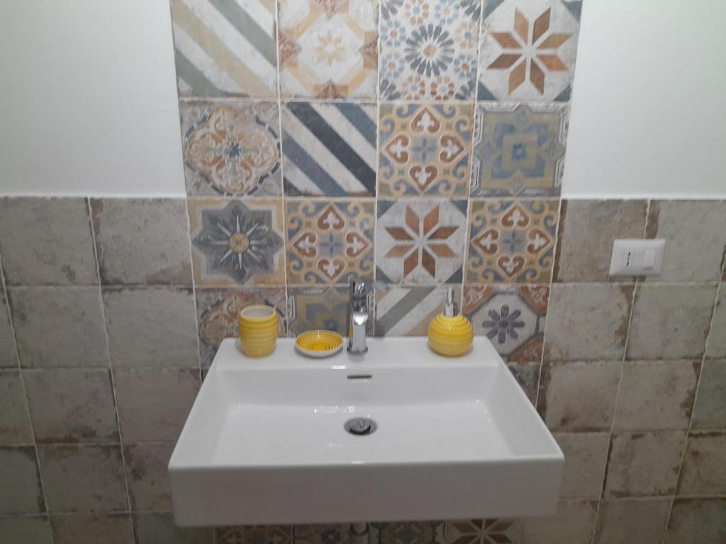 a white sink in a bathroom with tiles at La Coccola in Leporano