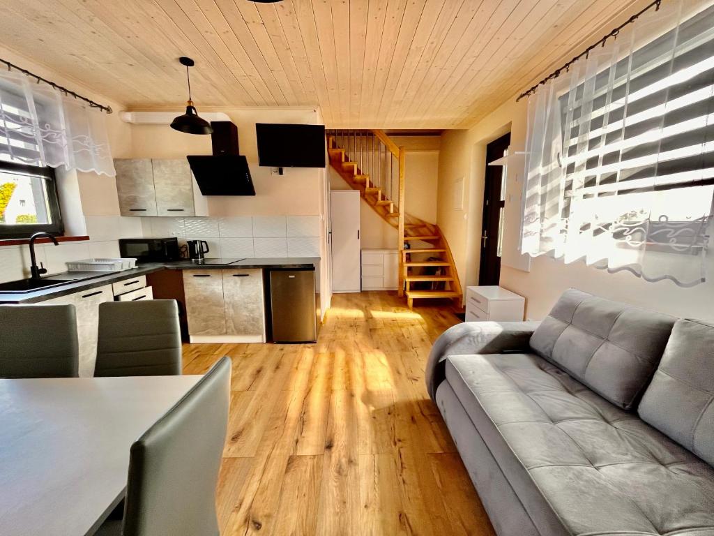 a living room with a couch and a table and a kitchen at Apartament na Ogrodowej - 2 sypialnie, ogród, taras, parking in Trzęsacz