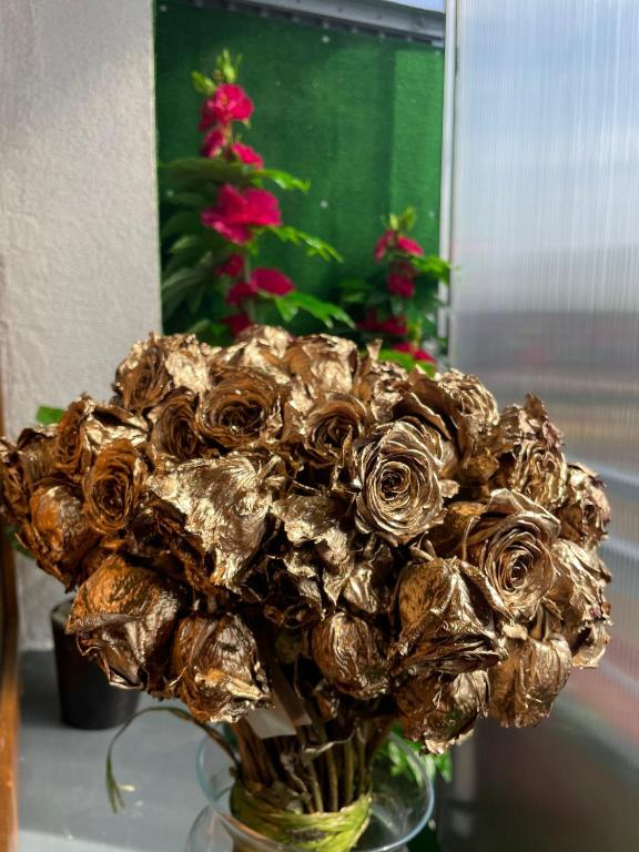 a vase filled with a bouquet of gold roses at LUXURY GOLD APARTMENT by Marta in Radom