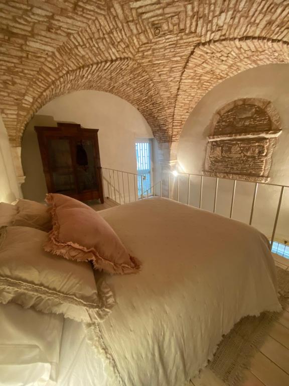 a bedroom with a large white bed with a brick ceiling at PalazzOliva - Boho chic Guest house in the historic heart of Martina Franca in Martina Franca
