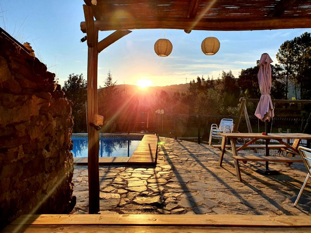 um pátio com uma mesa e uma piscina com o pôr-do-sol em Quinta do Castanheiro em Castanheira de Pera