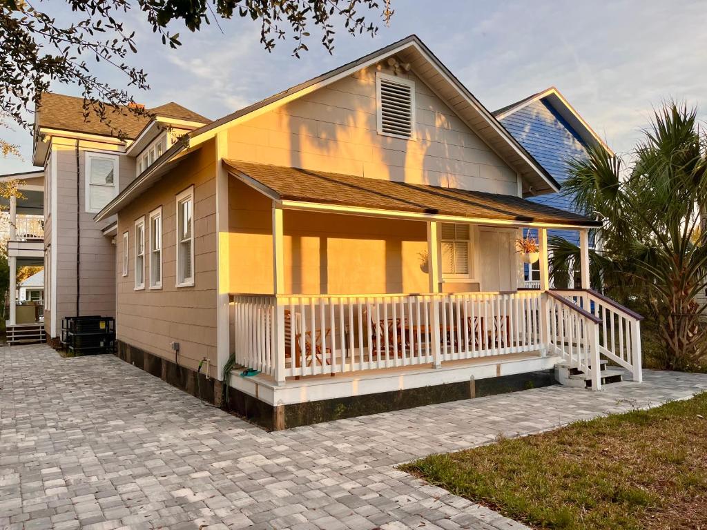 een geel huis met een veranda en een oprit bij Lovely Guesthouse in the Up-and-Coming Springfield in Jacksonville
