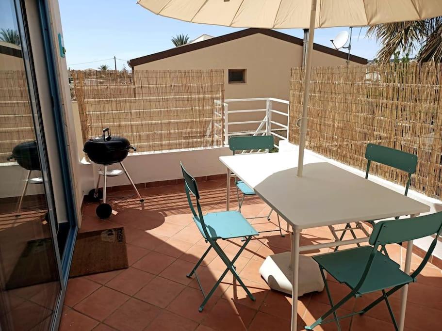 een patio met een tafel en stoelen en een parasol bij Casa dei Fiori in Donnalucata