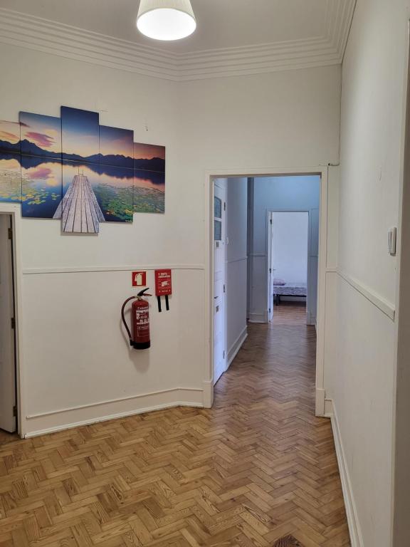 a hallway with white walls and wooden floors and paintings on the wall at Rainbow Guest House in Lisbon