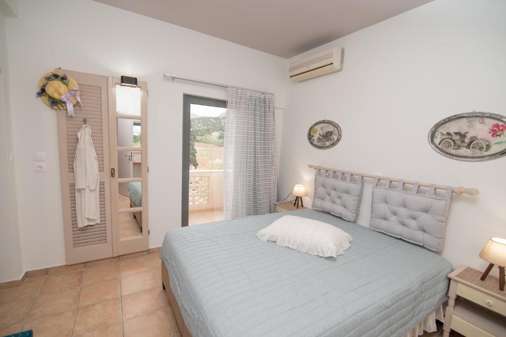 a white bedroom with a bed and a window at Tsaner Apartment and Rooms in Matala