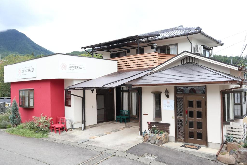 una casa rossa e bianca con una panchina rossa davanti di Sun Terrace Bessho Onsen - Vacation STAY 21387v a Ueda