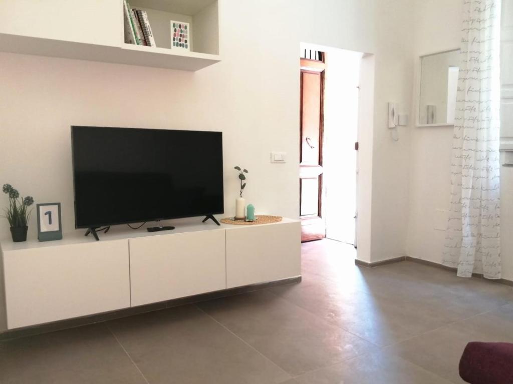 ein Wohnzimmer mit einem Flachbild-TV auf einem weißen Schrank in der Unterkunft Casa Clementina in Pisa