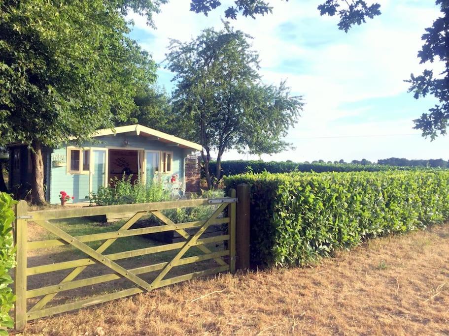 a fence in front of a small house with a gate at Tranquil Log Cabin - Beautiful Rural Sunset Views in Weston Longville