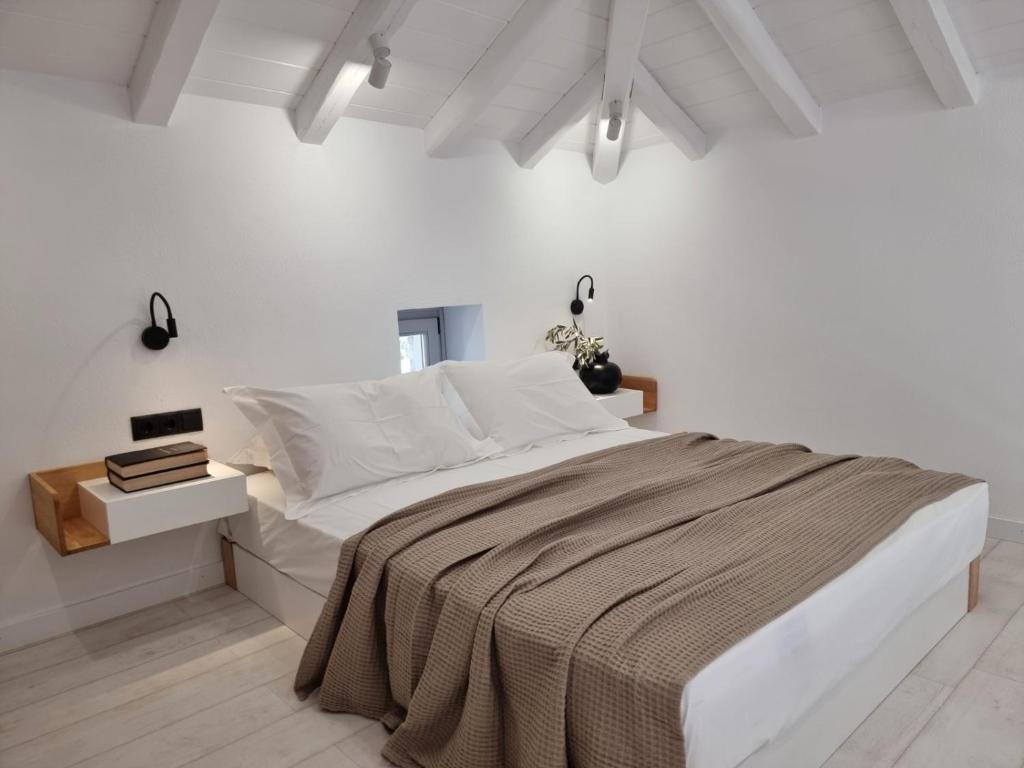 a white bedroom with a large bed and a table at Stone build suite with private pool in Kolios