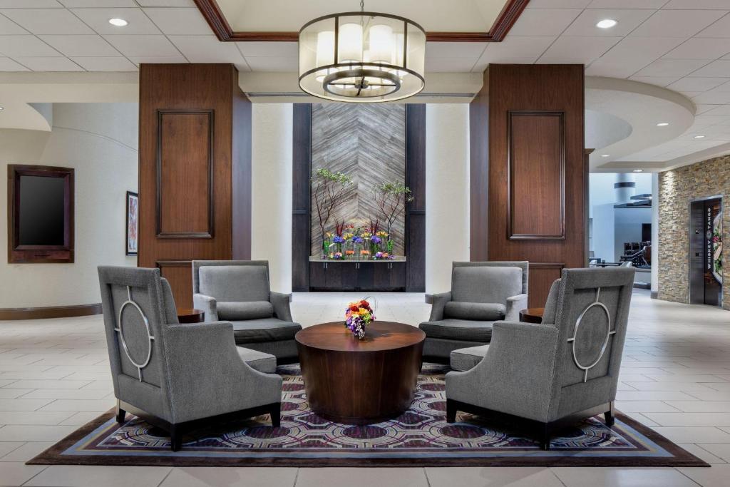 a lobby with chairs and a table and a chandelier at Sheraton DFW Airport Hotel in Irving