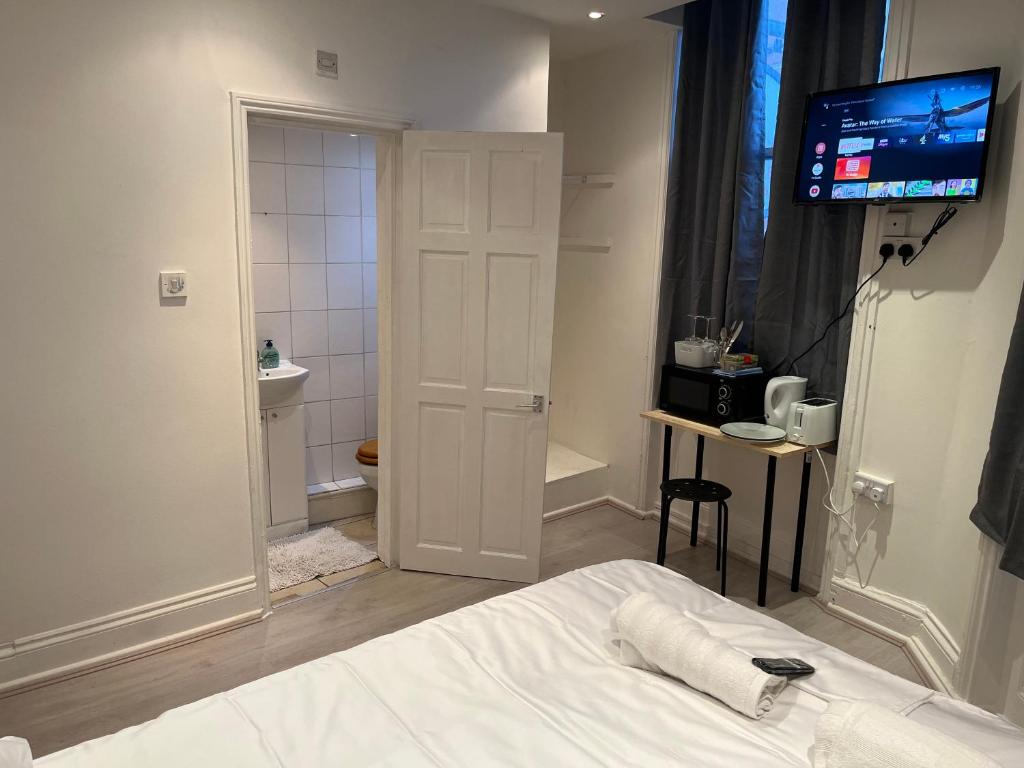 a bedroom with a bed with a television and a bathroom at Y2 guest house in London