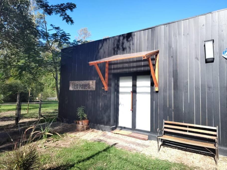 un edificio negro con un banco delante en La Pausa Casa Rural en A. de la Cruz