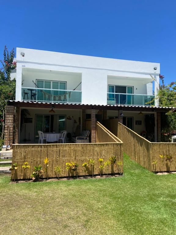een huis met een houten hek in de tuin bij Ville Santorinni in Japaratinga