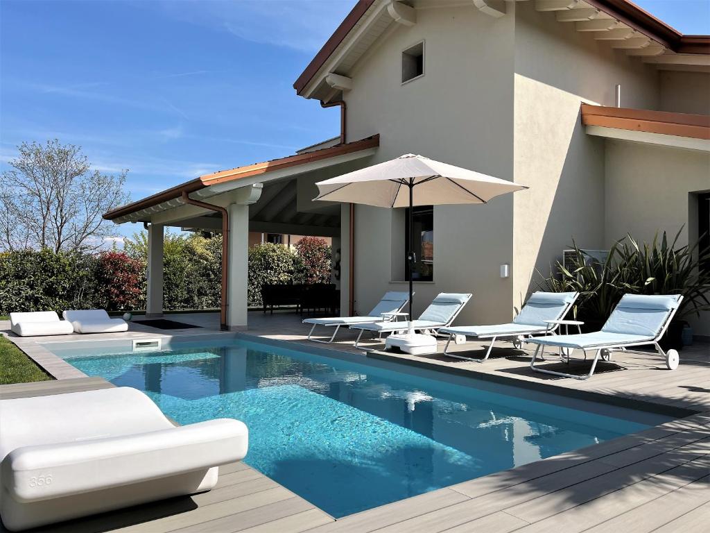una piscina con sillas y una sombrilla junto a una casa en Ferienhaus Casa sulle colline di Barcuzzi pool, garden and barbecue, en Barcuzzi