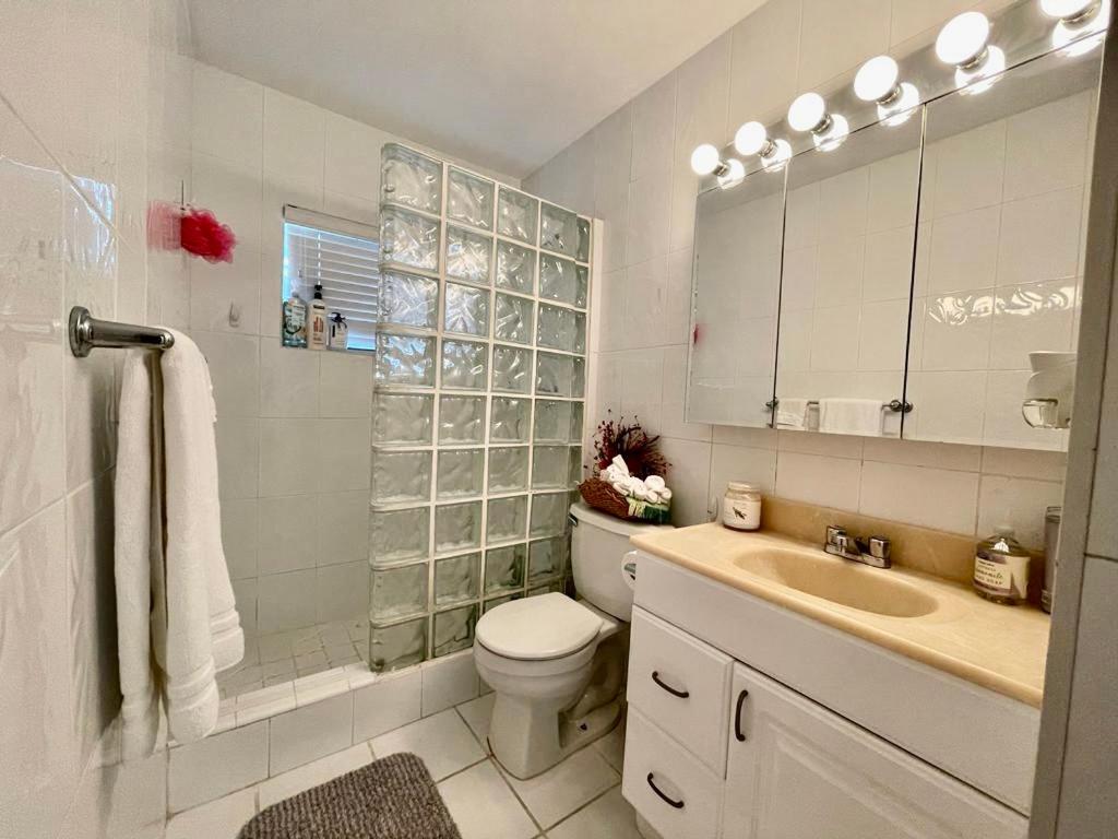 a white bathroom with a toilet and a sink at Queen's Tropical Garden View Room in Palmetto Bay