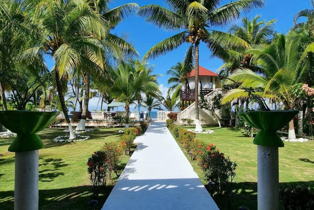 a walkway leading to a resort with palm trees at Huellas en la arena Casa De Playa in Tela