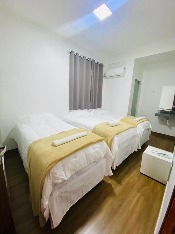 2 camas en una habitación con suelo de madera en Hotel Santorine Plaza - Itabira - Próximo a Fundação Cultural Carlos Drummond Andrade, en Itabira