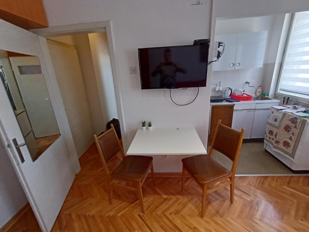 uma cozinha com uma mesa branca e uma televisão na parede em Apartman Natalija em Kuršumlija