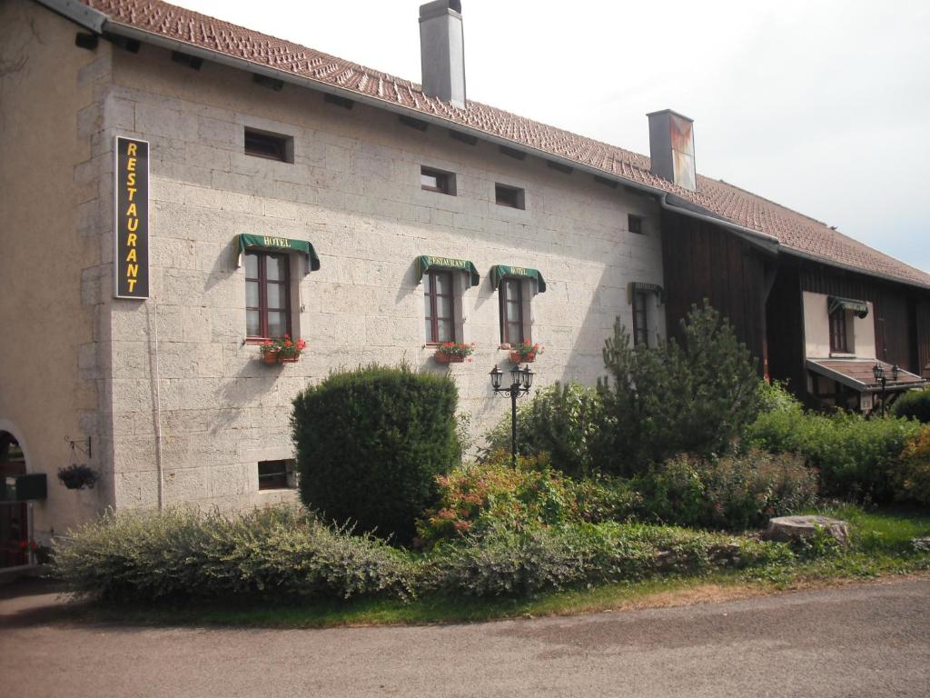 un edificio con tres ventanas con flores. en Auberge de la Motte, en Les Combes