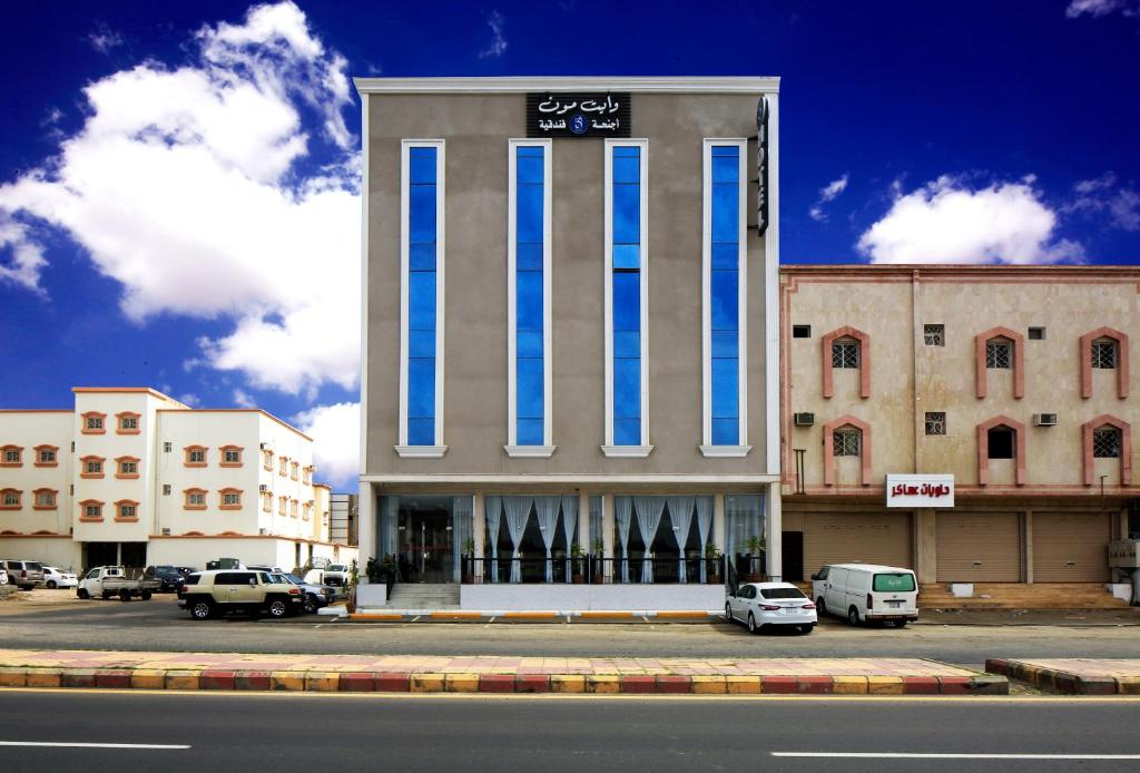 um edifício alto com colunas azuis e brancas numa rua em وايت مون للأجنحة الفندقية -الرصراص em Khamis Mushayt