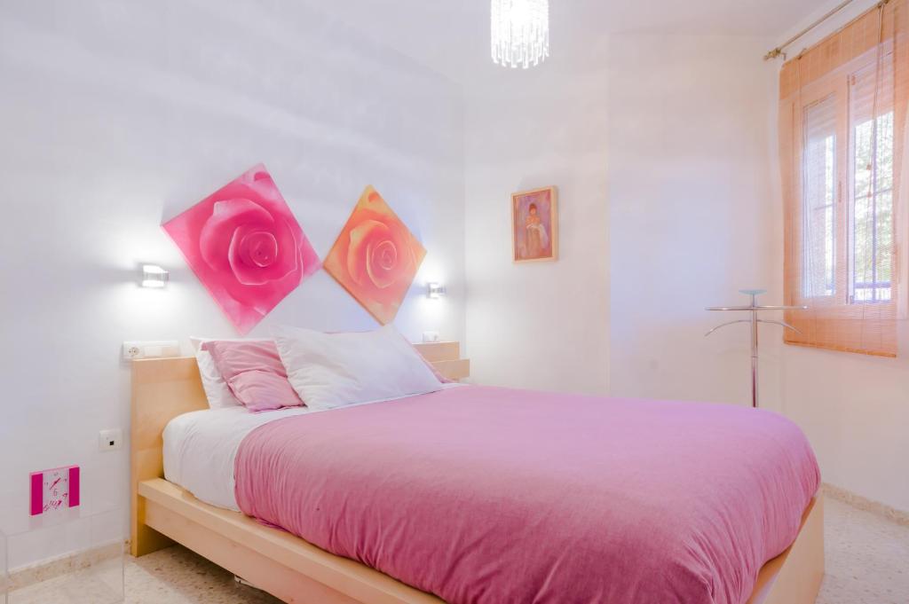 a bedroom with a bed with pink sheets and roses on the wall at Apartamentos Sanlúcar &amp; Doñana in Sanlúcar de Barrameda