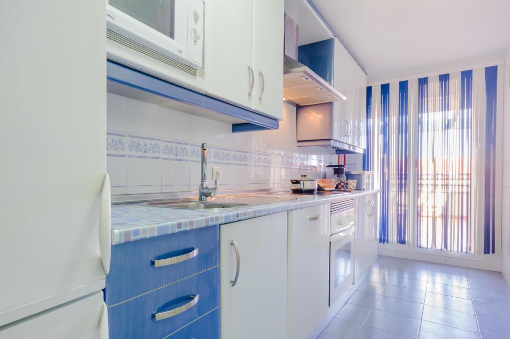 a kitchen with blue and white cabinets and a sink at Apartamentos Sanlúcar &amp; Doñana in Sanlúcar de Barrameda