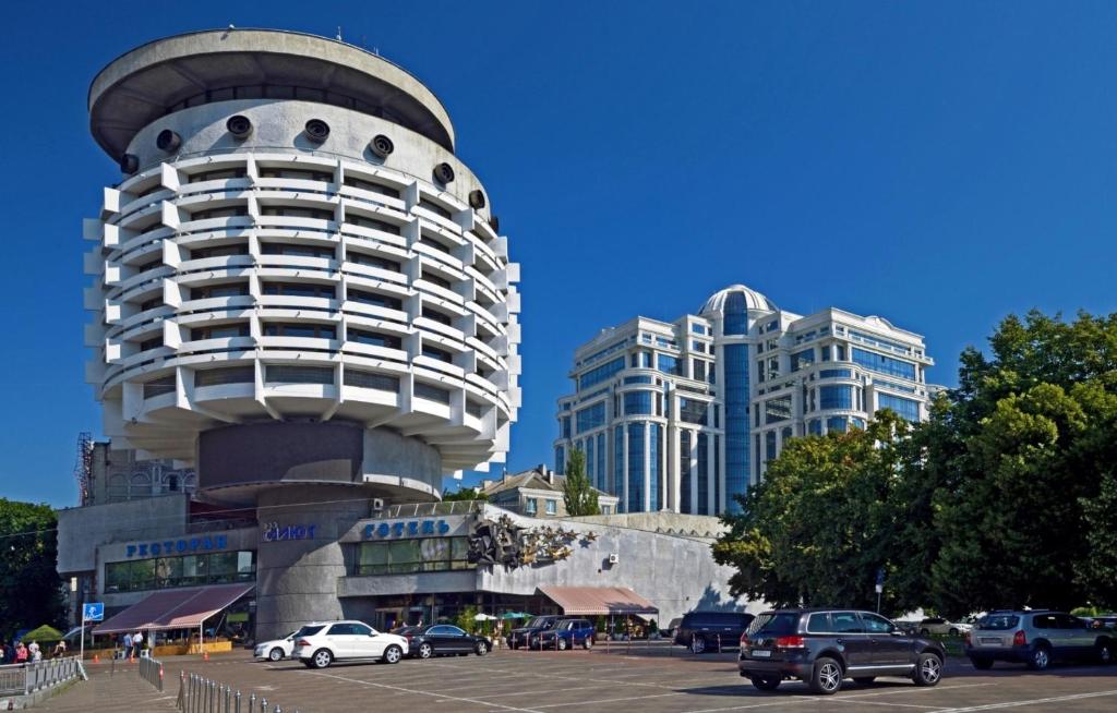 a tall building with cars parked in a parking lot at Salute Hotel in Kyiv