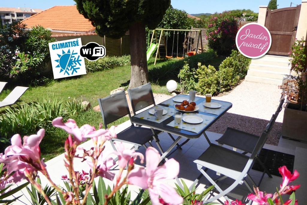 - une table et des chaises dans une cour fleurie dans l'établissement Bas de villa jardin plein sud proche mer clim-Wifi, à Saint-Mandrier-sur-Mer
