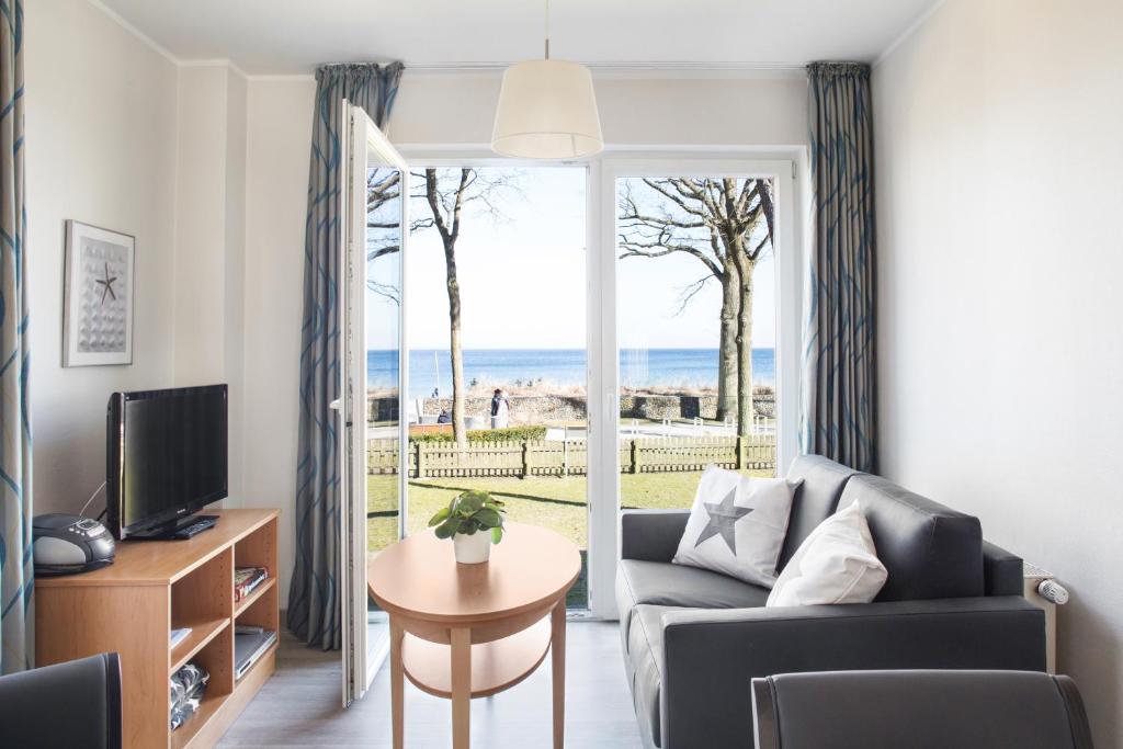 ein Wohnzimmer mit einem Sofa, einem Tisch und einem TV in der Unterkunft Apartmenthaus Seehof in Timmendorfer Strand