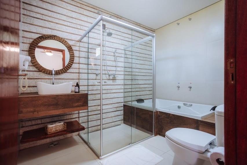 a bathroom with a shower and a toilet and a sink at Hotel Fazenda Vale Amanhecer in Igarapé