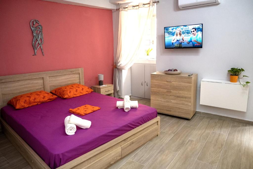 a bedroom with a purple bed and a tv on the wall at Maya Studio in Ermoupoli