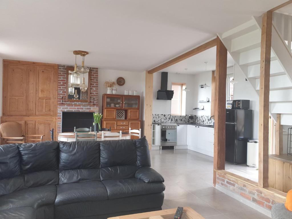 sala de estar con sofá negro y cocina en Le Moole Veld en Steenbecque