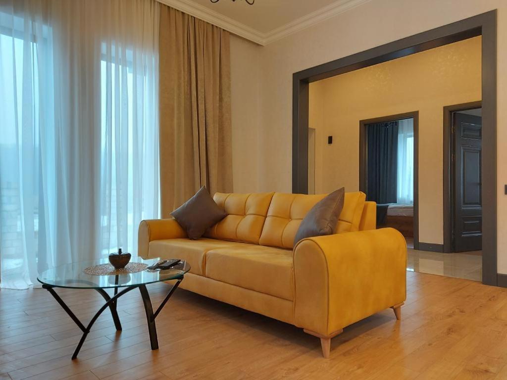 a living room with a yellow couch and a glass table at Chilagir_garden in Qusar