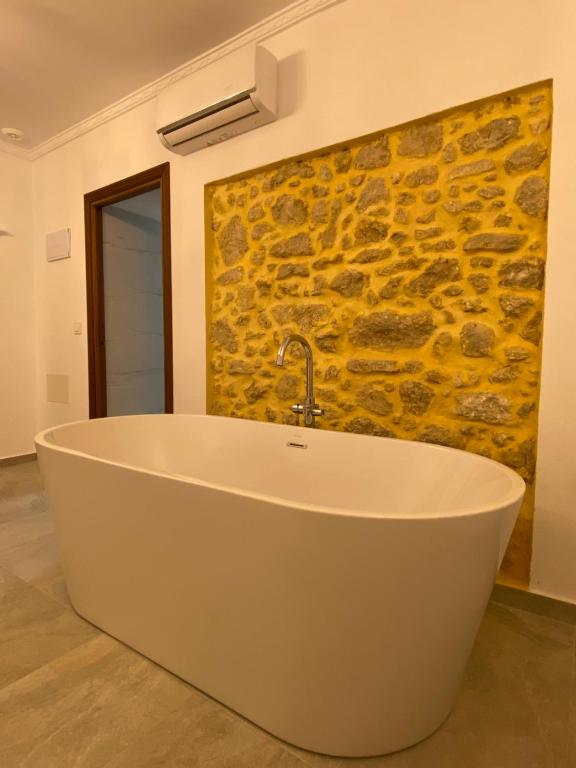y baño con bañera y pared de piedra. en Suites Benalup Centro, en Benalup-Casas Viejas