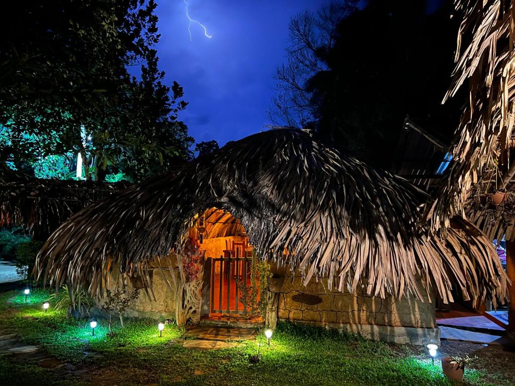 a thatch hut with a thatched roof at night at Hasthi Safari Cottage in Udawalawe