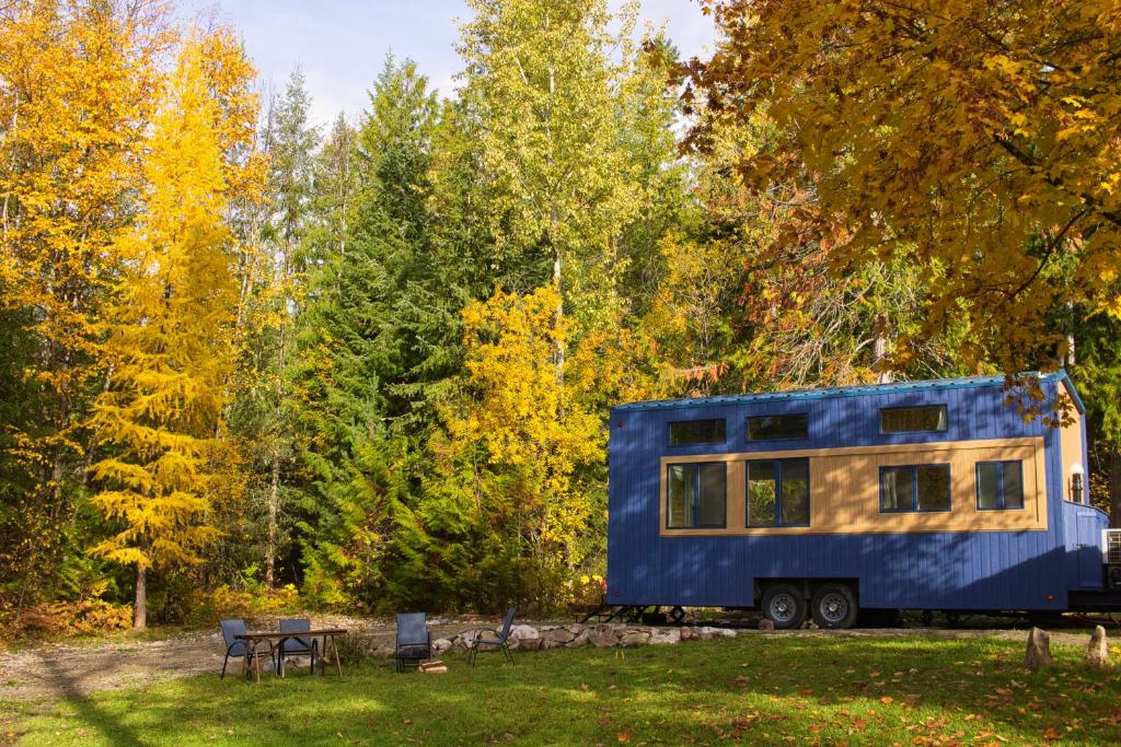 a blue tiny house parked in a field at Modern Private Tiny House in the Forest in Slocan