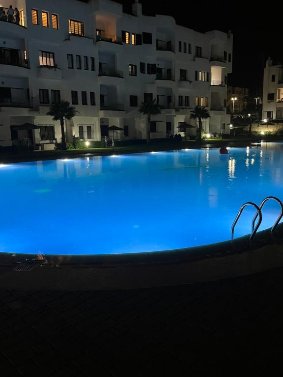 een groot zwembad 's nachts met blauwe verlichting bij Résidence Colina SMIR in M'diq