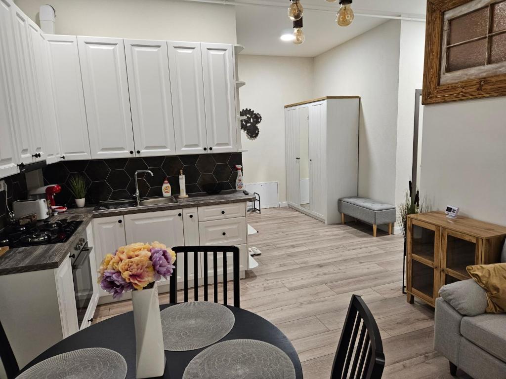 a kitchen and living room with white cabinets and a table at Cozy apartament in Sighetu Marmaţiei