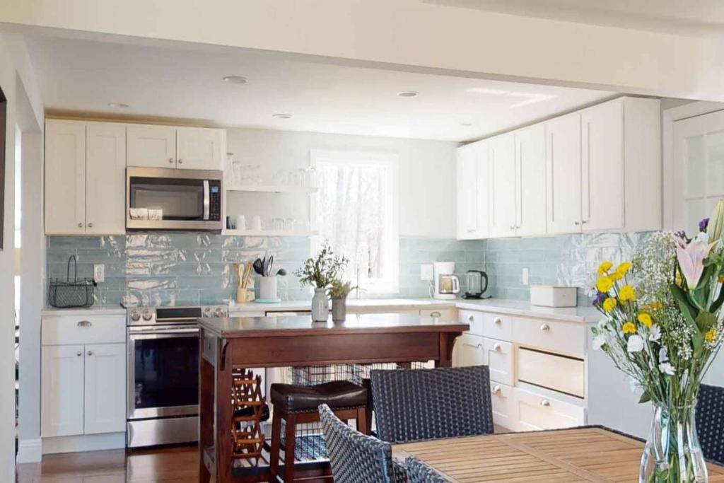 a kitchen with white cabinets and a table with chairs at White Oaks in Branford