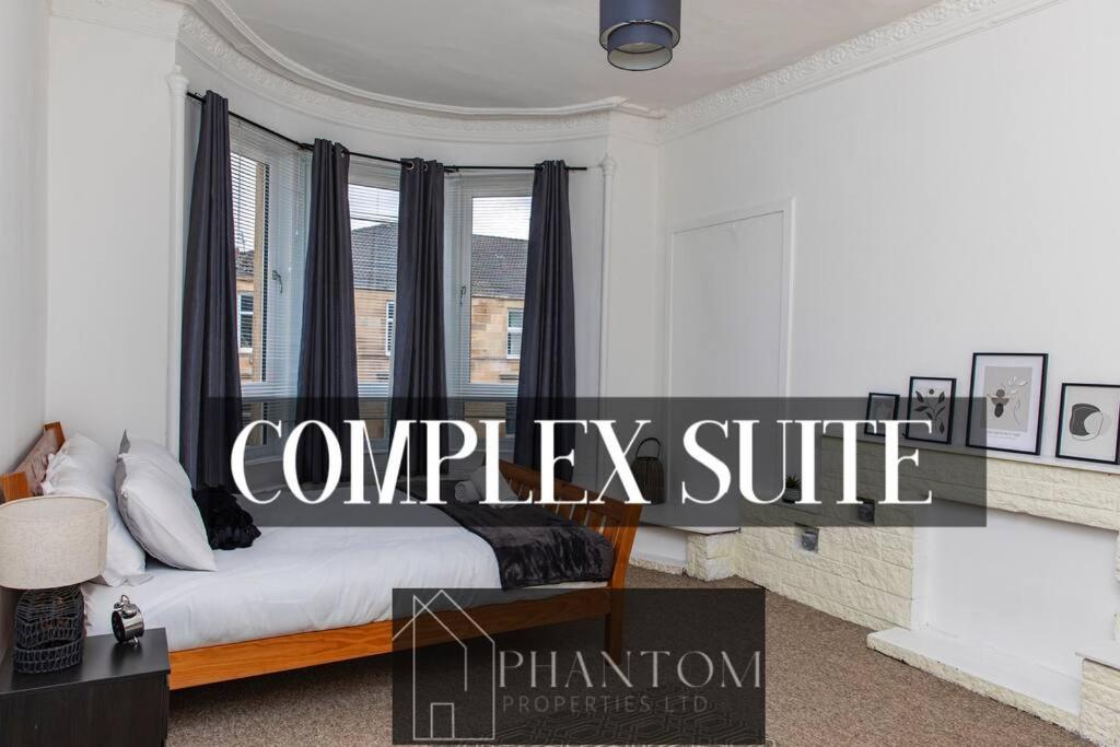 1 dormitorio con 1 cama con cortinas negras y ventana en Complex Suite, en Glasgow