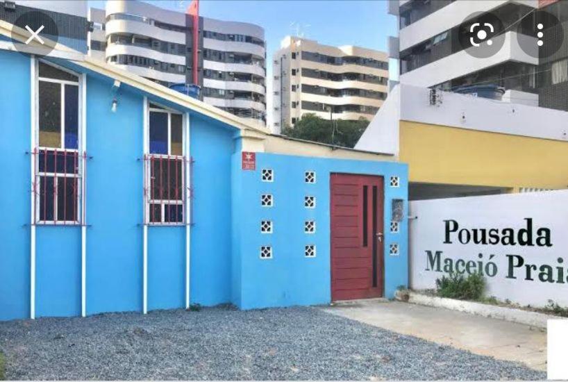 niebieski budynek z czerwonymi drzwiami w mieście w obiekcie Pousada Maceio Praia w mieście Maceió
