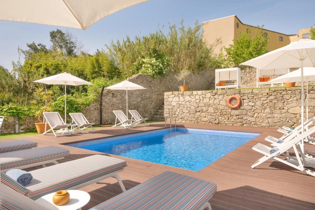 a pool with chairs and umbrellas in a yard at Santa Catarina - Pool & Fitness, by Oporto Collection - Adults Only in Porto